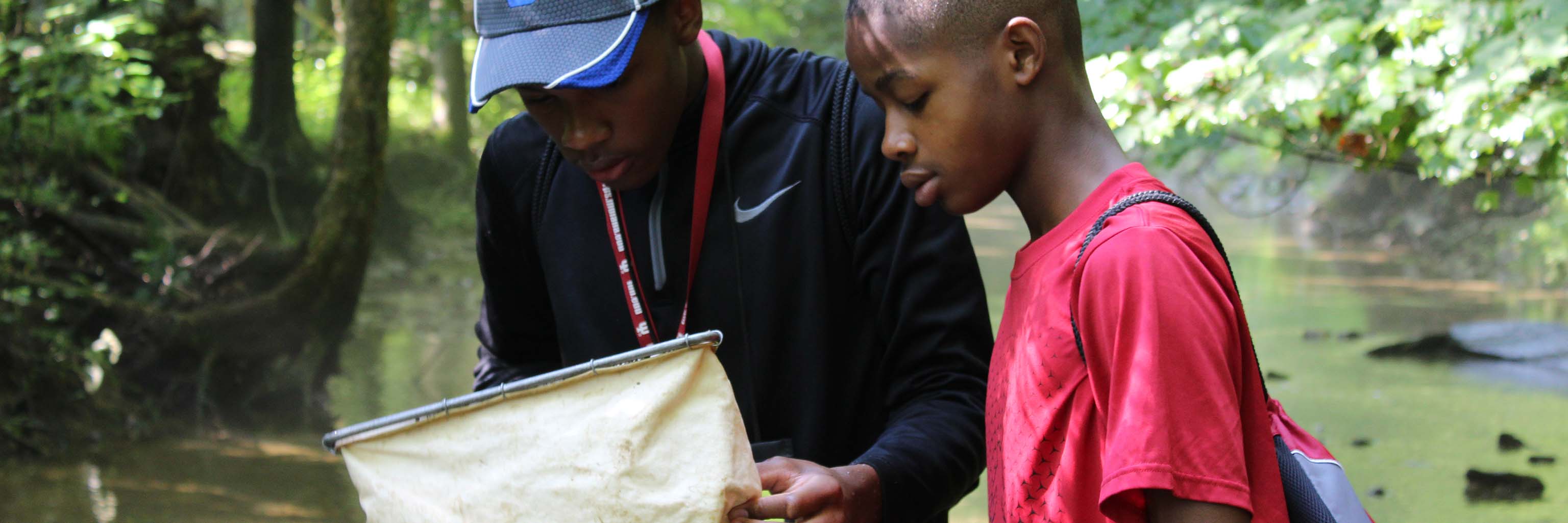 Two students checking their net to see what they caught from the stream during a Riverwatch activity.