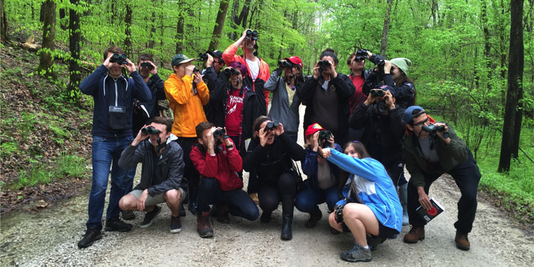 A group of students looking through binoculars as birds.