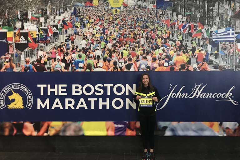 Olivia Ballew poses in front of The Boston Marathon sign.