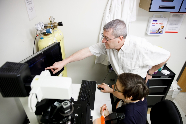 Amelia Randich and Yves Brun work with a microscope in Brun's lab.