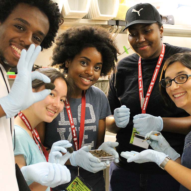 Students smile as they pose for a photo while holding up the brood balls they just made in the Moczek lab.