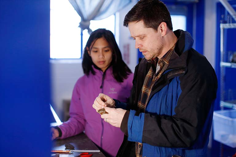 Adam Fudickar showing Lia Bobay how to apply a leg band to a Fox Sparrow.