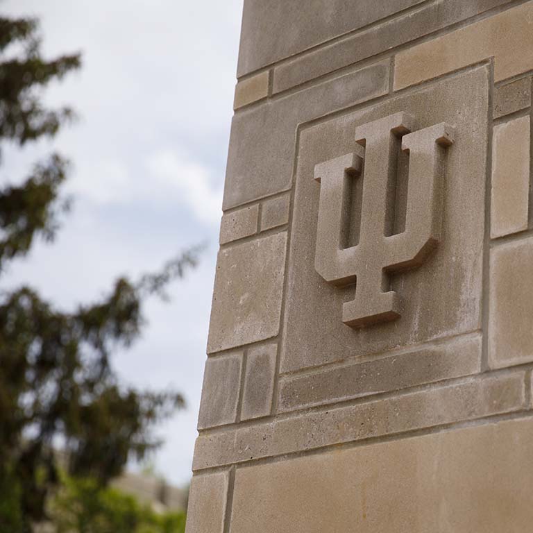 The IU trident carved in limestone is displayed in a stone-block pillar.